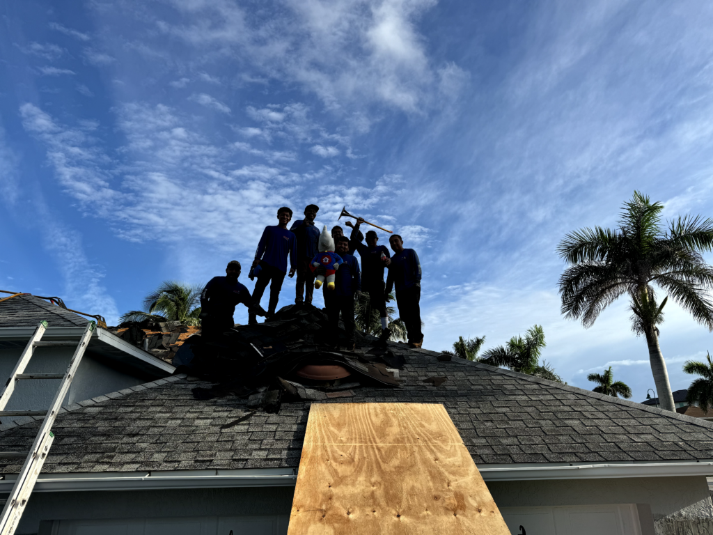 Professional roofing crew on roof marking completion of a project with satisfied results