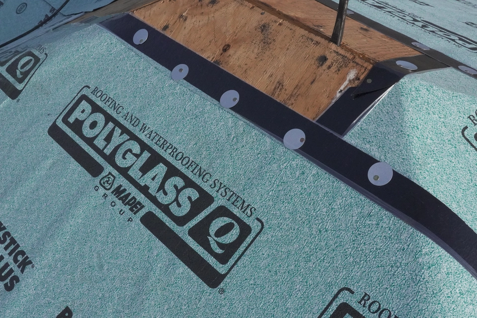 Expert applying waterproof sheet to roof for safe and long-lasting protection.