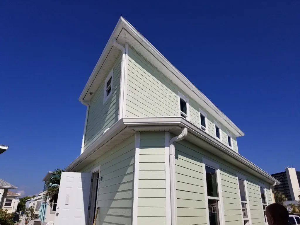 Completed roof with white gutters and siding providing durable protection and clean aesthetic.